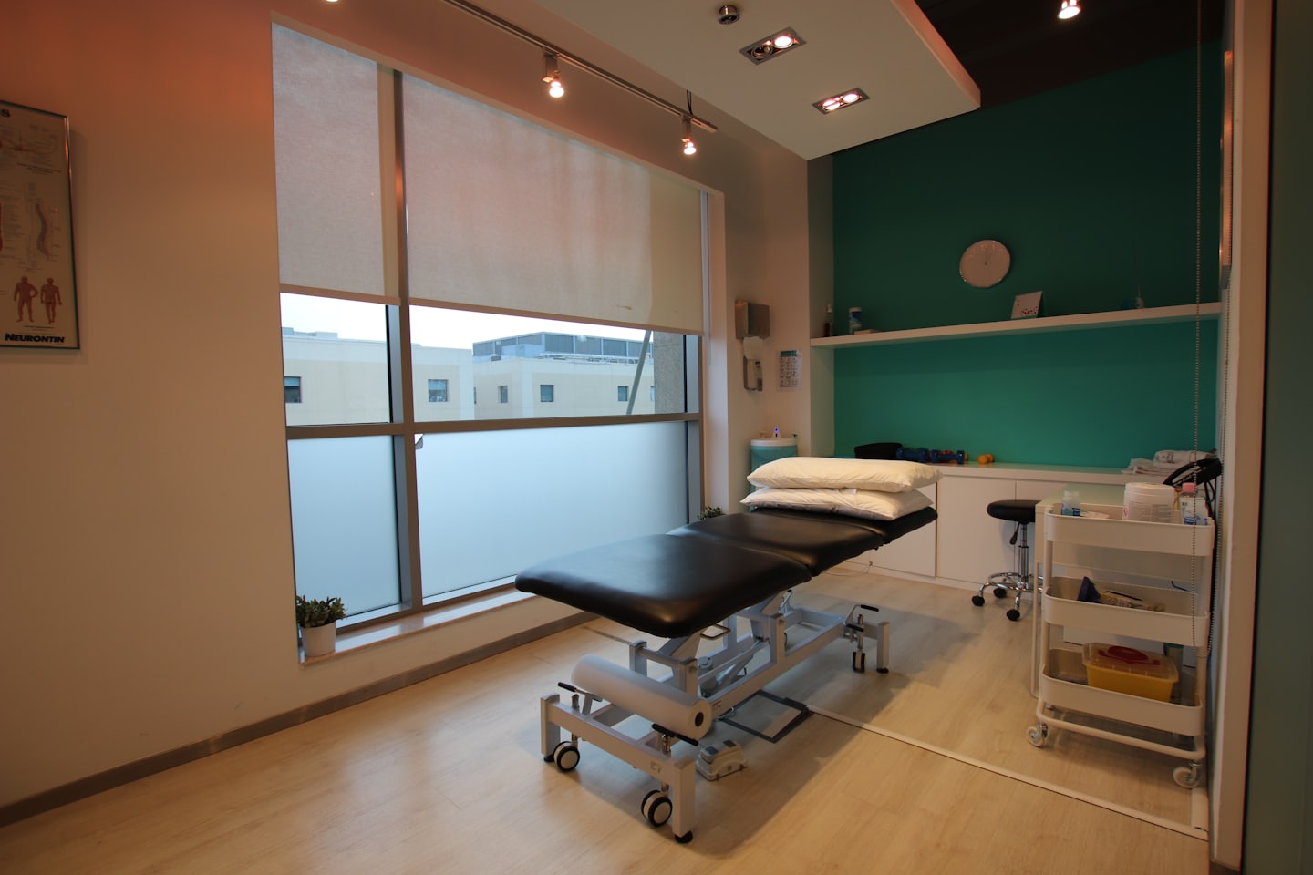 Modern examination room with teal accent wall and examination table.